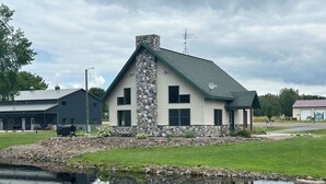 A house with a stone facade, a green roof, and a pond in front. - National Forest, Fishing, Trail riding, Hunting, Bars/Eatery and Pet-Friendly (Gilman)