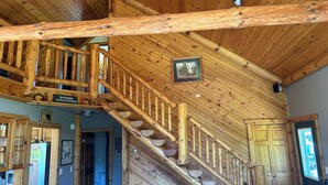 A wooden staircase with a rustic design, a sign reading "Welcome to The Cabin," and a door with a window. - National Forest, Fishing, Trail riding, Hunting, Bars/Eatery and Pet-Friendly (Gilman)