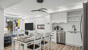 Une cuisine moderne avec des meubles blancs, un four encastré et un réfrigérateur en acier inoxydable.