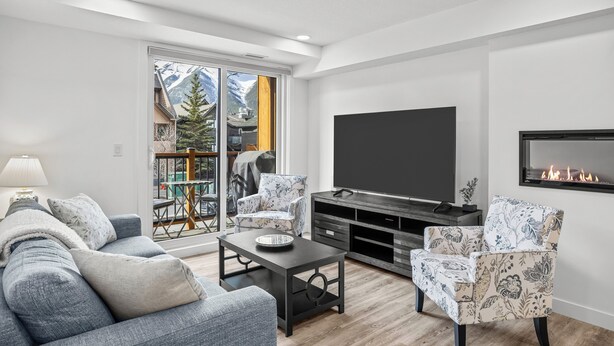 Un salon moderne comprenant un canapé, des fauteuils, une table basse, un téléviseur et une cheminée.