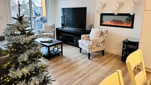 Un salon moderne avec un grand téléviseur à écran plat, une cheminée et un sapin de Noël.