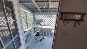Eine Veranda mit einer weißen Bank, einem Kaktus und einem Willkommensschild.