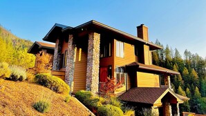 Une maison à deux étages avec des piliers en pierre, une porte rouge et une cheminée.