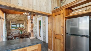 Une cuisine au décor intérieur en bois, avec un réfrigérateur en acier inoxydable et un coin repas comprenant une table et des chaises.