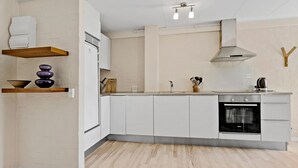 Una cocina moderna con armarios blancos, horno empotrado y encimera de madera.