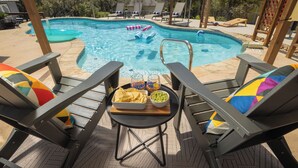 Ein Poolbereich mit zwei Liegestühlen, einem kleinen Tisch mit Snacks und Getränken und Blick auf den Pool.