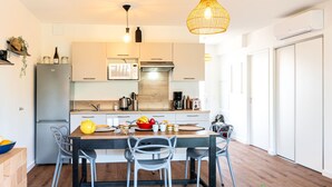 A modern kitchen with a wooden dining table, grey chairs, and a hanging light fixture. - Jade et Elena by Interhome (Lit-et-Mixe)