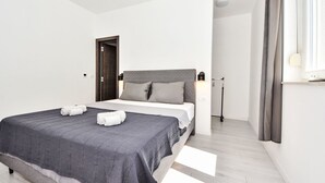 A modern bedroom with a bed, a bedside table, a lamp, and a window with curtains.