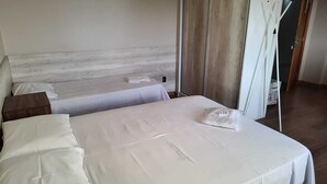 Ein ordentlich bezogenes Bett mit weißen Leinentüchern und einem hölzernen Kopfteil.