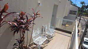 Ein Balkon mit weißen Metallstühlen und einem Blumentopf.