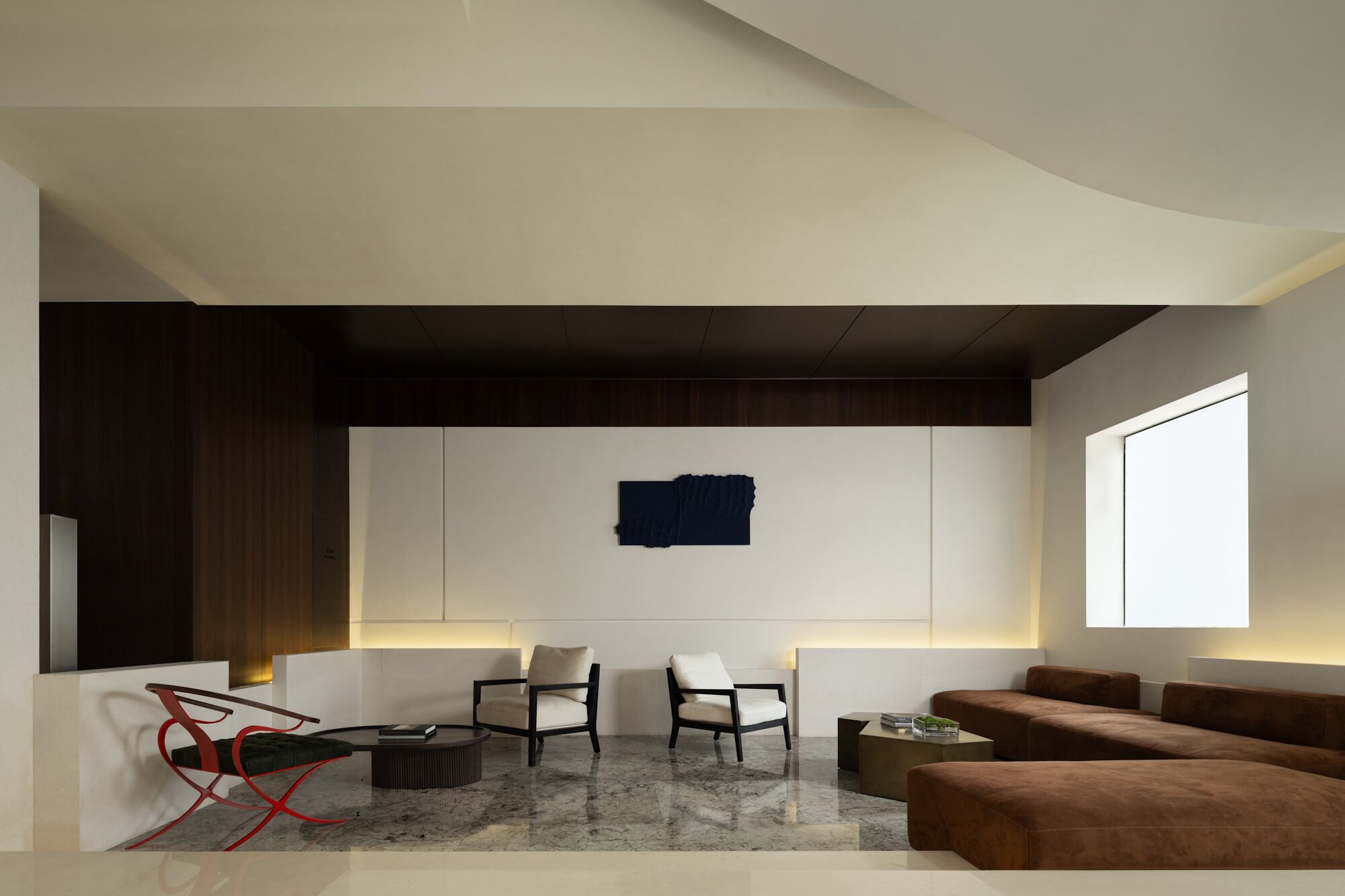 A modern living room with a minimalist design, featuring a sofa, two chairs, a coffee table, and a unique wall art piece.