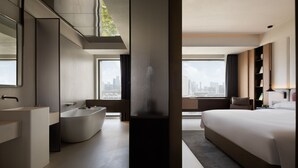 A modern hotel room with a large bed, a bathtub, a large window with a city view, and a large mirror. - Book'in Hotel (Changsha)