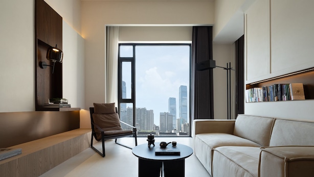 A modern hotel room with a city view, a sofa, a chair, a coffee table, and a bookshelf. - Book'in Hotel (Changsha)