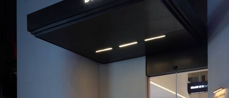 Una entrada de hotel moderna con un letrero que dice 'BOOK IN HOTEL', una puerta de cristal y un diseño limpio y minimalista.