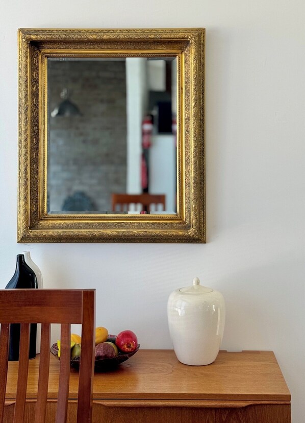 Een houten tafel met een witte vaas en een schaal vol fruit.
