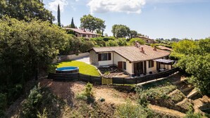 Una villa con piscina, immersa nel verde e circondata da colline.