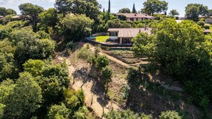 Paesaggio rurale con una casa immersa nel verde e alberi.