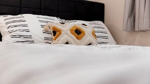 Een bed met gestreept beddengoed en een decoratief kussen.