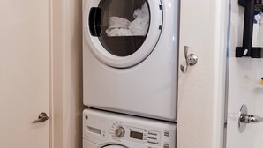 Een kleine, praktische wasruimte met een wit wasmachine en droger die verticaal boven elkaar zijn geplaatst.