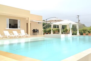 Una piscina al aire libre, sillones reclinables de piscina