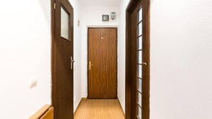A narrow hallway with wooden doors and a tiled floor. - Jazzy Studio in the Heart of Bucharest (București)