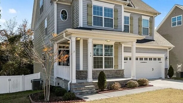 A two-story house with a front porch, garage, and a well-maintained lawn.
