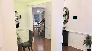 A spacious room with hardwood flooring, a dining area with a table and chairs, and a staircase leading to another level.