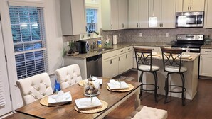 A modern kitchen with white cabinetry, a central island with bar stools, and pendant lighting.