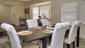 A dining area with a dark wooden table, white upholstered chairs, and a ceiling fan. - Cozy Family Retreat: Coffee Bar, Game Room and Pet Friendly (Lodi)