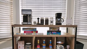 A wooden coffee station with a coffee maker, jars of coffee beans, and various coffee-related items. - Cozy Family Retreat: Coffee Bar, Game Room and Pet Friendly (Lodi)