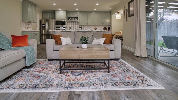 A modern living room with a grey sofa, a wooden coffee table, and a patterned rug. - Cozy Family Retreat: Coffee Bar, Game Room and Pet Friendly (Lodi)