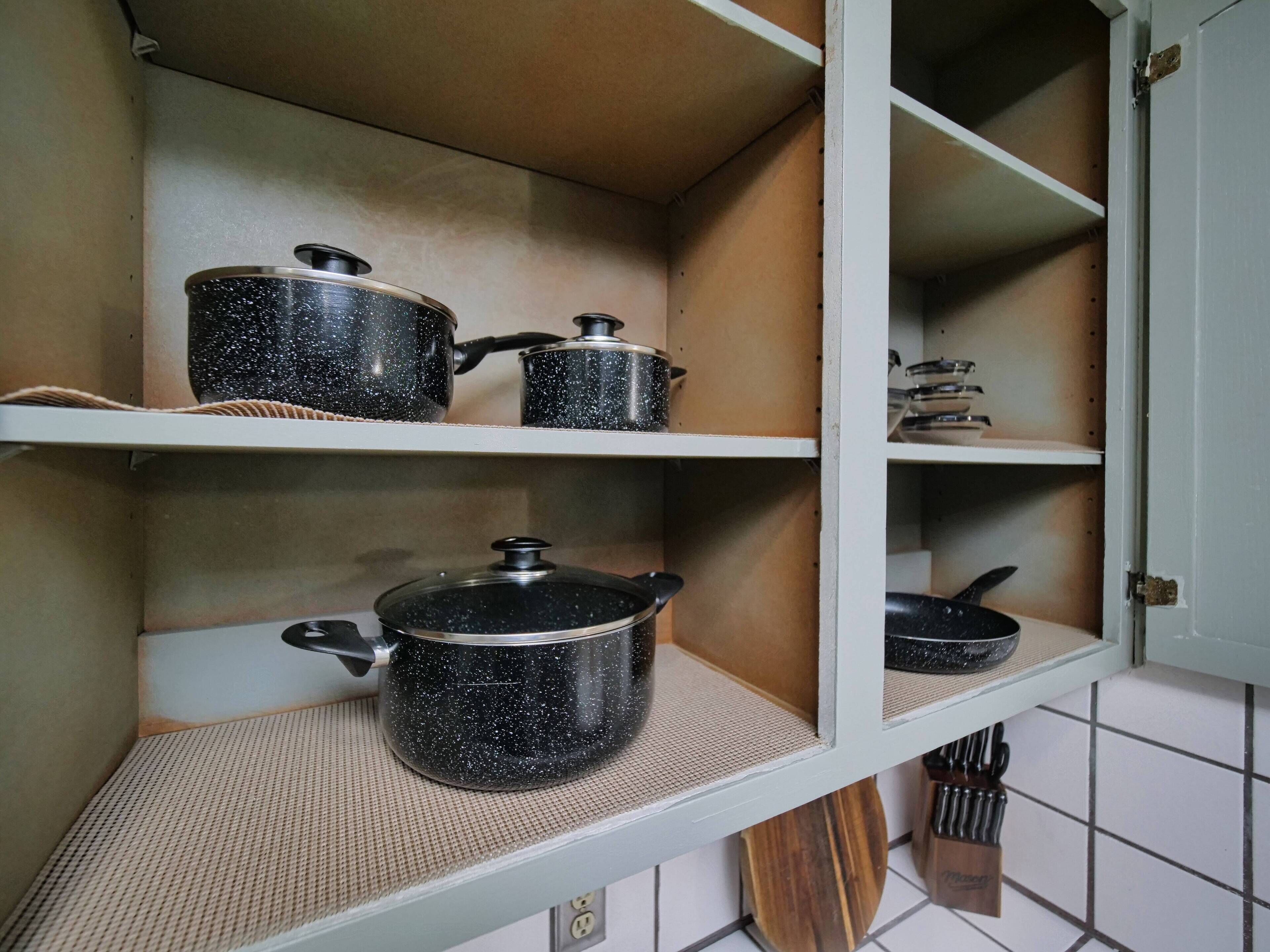 A kitchen shelf with two black speckled pots and a knife block.