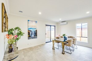 Un comedor amplio con una mesa y sillas modernas, un jarrón de flores y un cuadro en la pared.