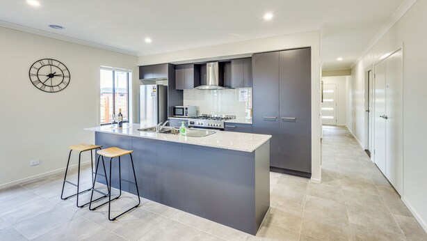 A modern kitchen with a central island, bar stools, a microwave, and a stove.