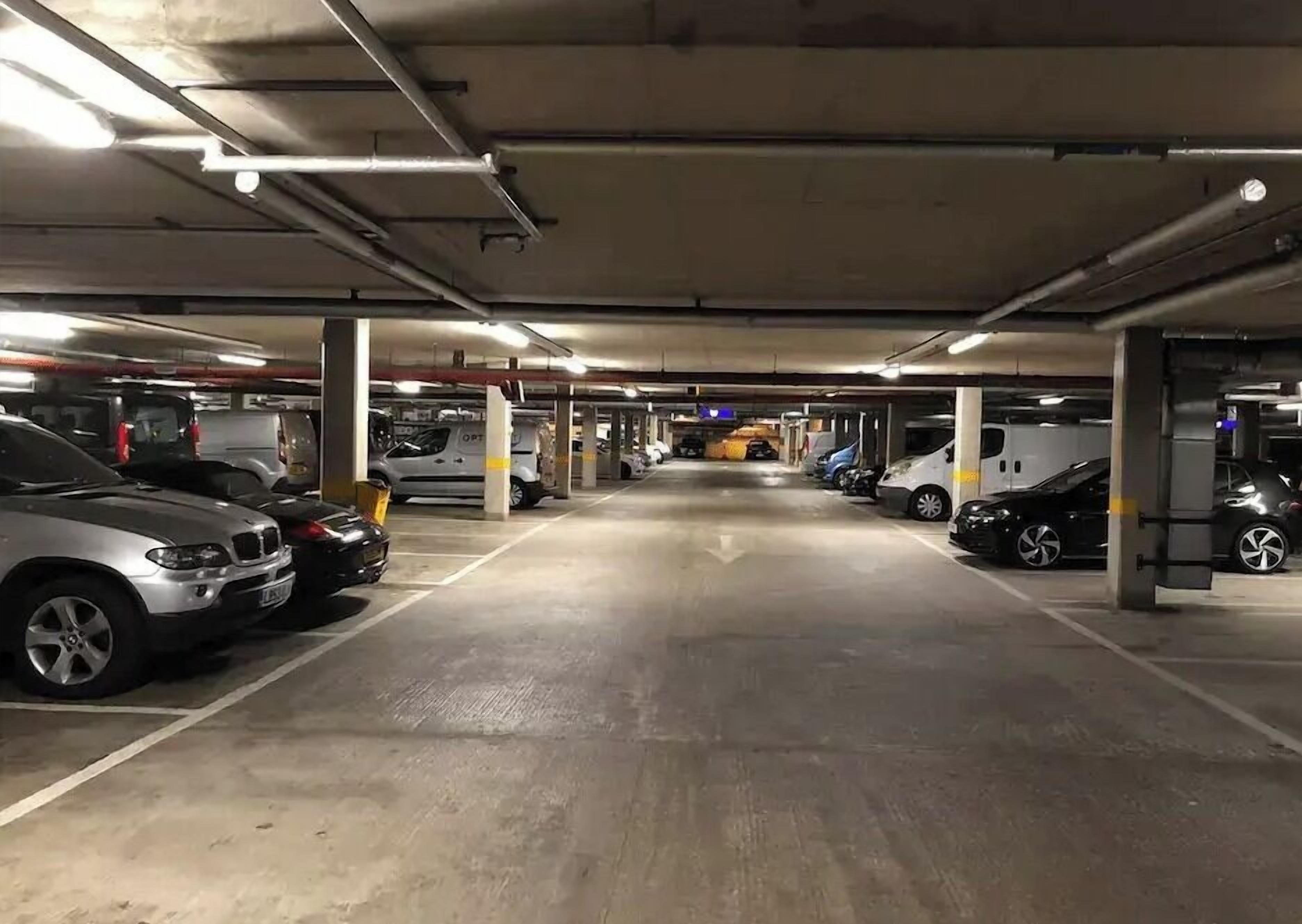 Un parking souterrain à plusieurs niveaux, avec des piliers en béton et un éclairage au plafond.