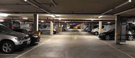 Un parking souterrain à plusieurs niveaux, avec des piliers en béton et un éclairage au plafond.