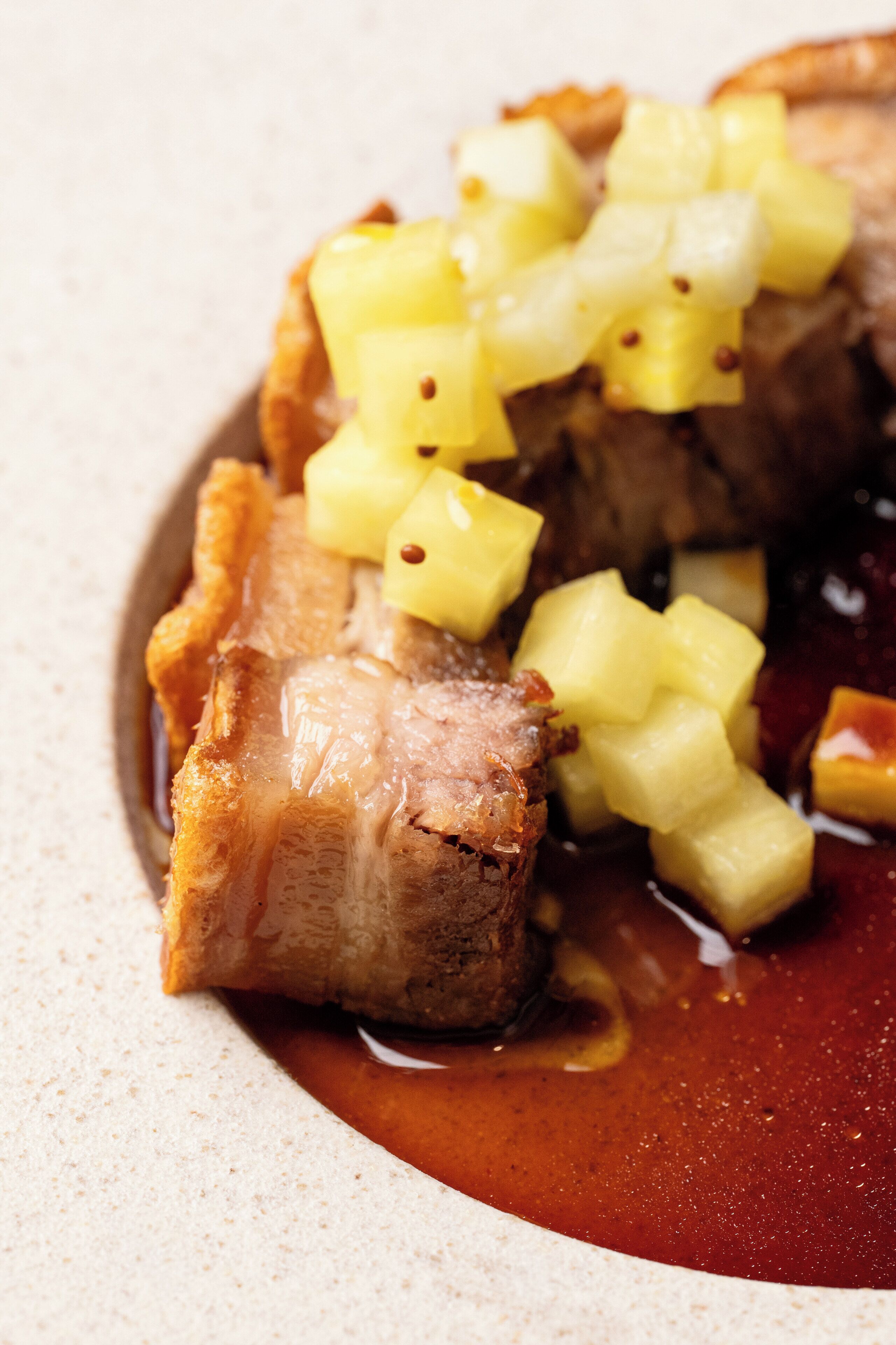 A close-up of a dish with meat and pineapple chunks.