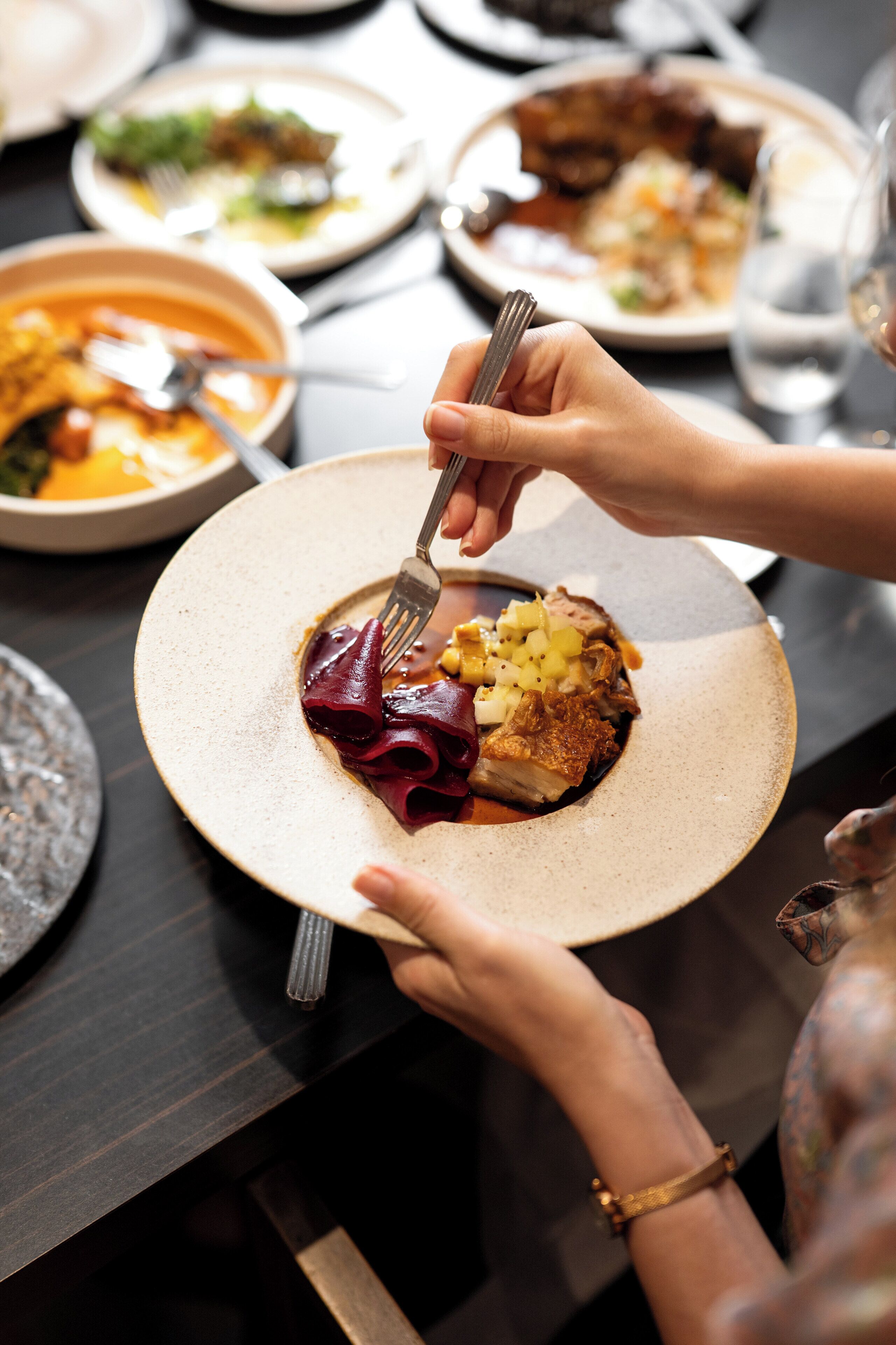 A dining table with plates of food, a fork, and a glass of water.