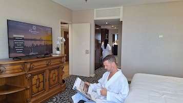 Habitación de hotel con una televisión de pantalla plana grande, cómoda de madera, alfombra estampada y una cama.