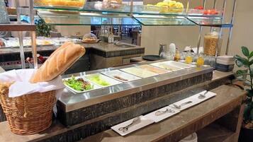 A buffet with various food items, including bread, salads, and fruits.