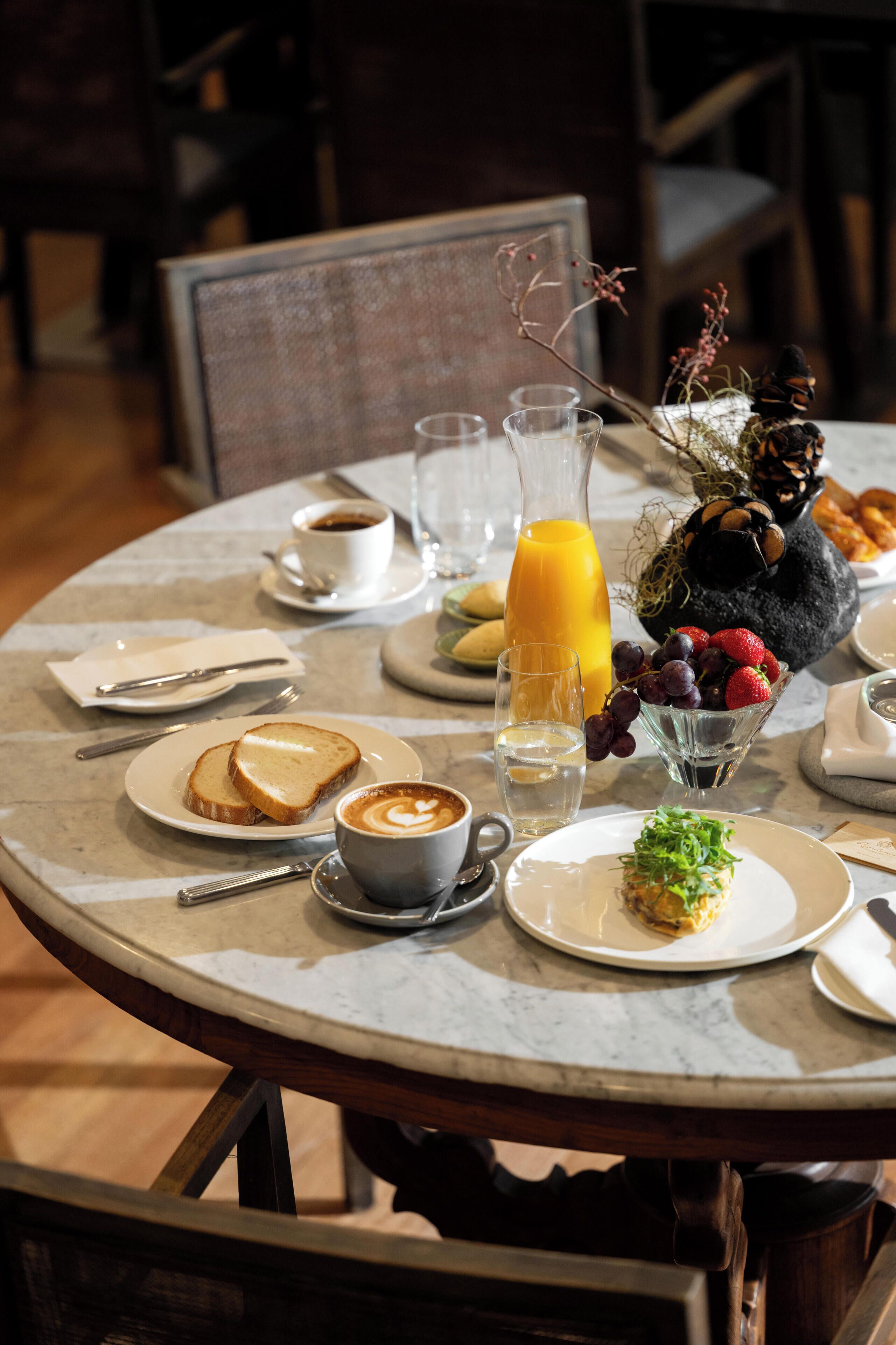 A round dining table with breakfast items, including toast, coffee, and fruit.