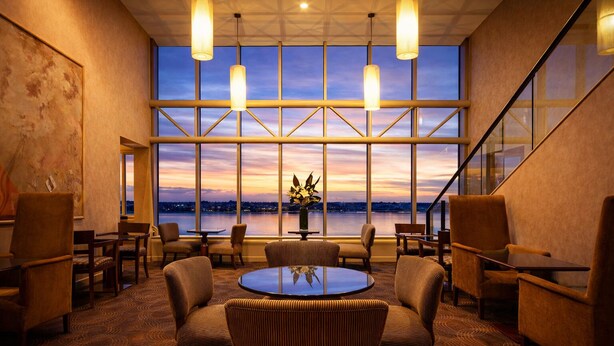 A conference room with a large table, chairs, and a view of the cityscape at sunset. - Residence on Langley Park (East Perth)