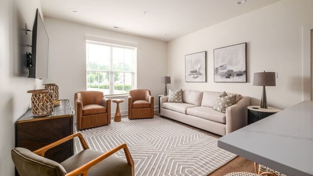 A modern living room with a sofa, two armchairs, a coffee table, and a TV mounted on the wall. - Beautiful Main Street Living in Trussville  (Trussville)