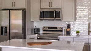 A modern kitchen with stainless steel appliances, a marble countertop, and pendant lighting. - Beautiful Main Street Living in Trussville  (Trussville)
