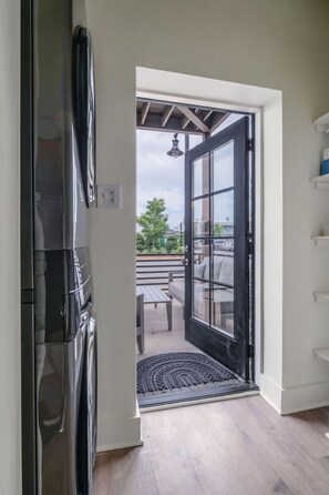A kitchen with a black refrigerator, a door leading to an outdoor patio with a table and chairs, and a view of the outside. - Beautiful Main Street Living in Trussville (Trussville)