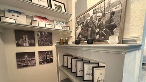 Un pasillo con cuadros en estantes y en la pared, y una escalera con barandilla decorativa.