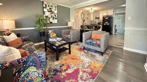 Una sala de estar con ventilador de techo, una mesa de centro y sofás estampados.