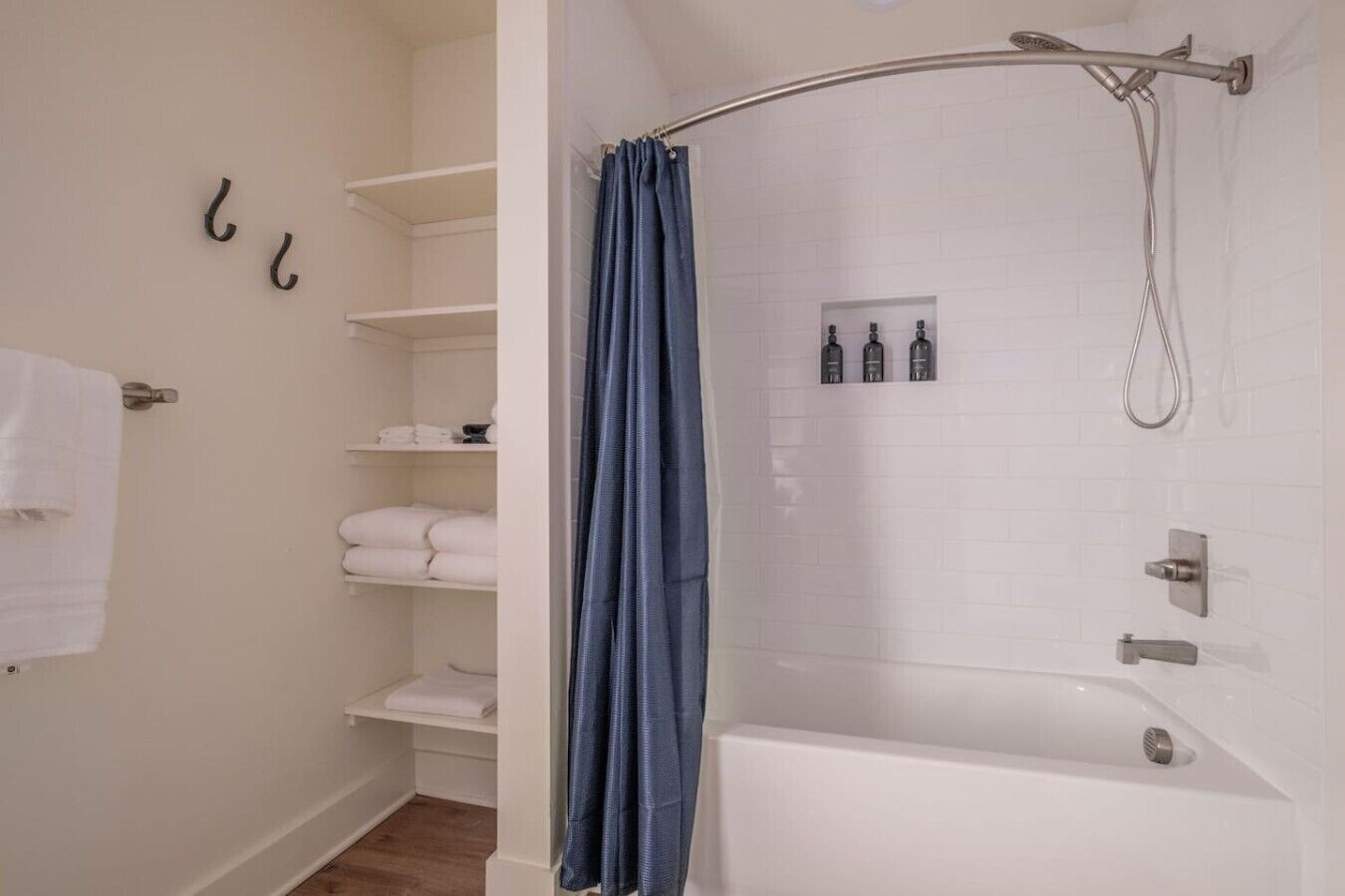Une salle de bain avec une douche, un porte-serviettes et une étagère où sont pliés les serviettes.