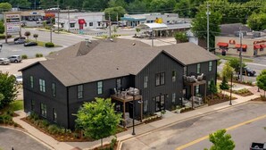 A modern two-story building with a flat roof, large windows, and a balcony on the second floor. - 5 Star Flat Downtown Trussville (Trussville)