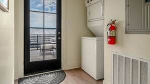 A compact kitchen with a built-in washer and dryer, a fire extinguisher mounted on the wall, and a view of the balcony. - 5 Star Flat Downtown Trussville (Trussville)